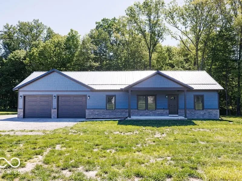 Front exterior of 4538 Country Club Rd in Spencer, Indiana: a new construction ranch with a metal roof, stone accents, and a covered front porch.