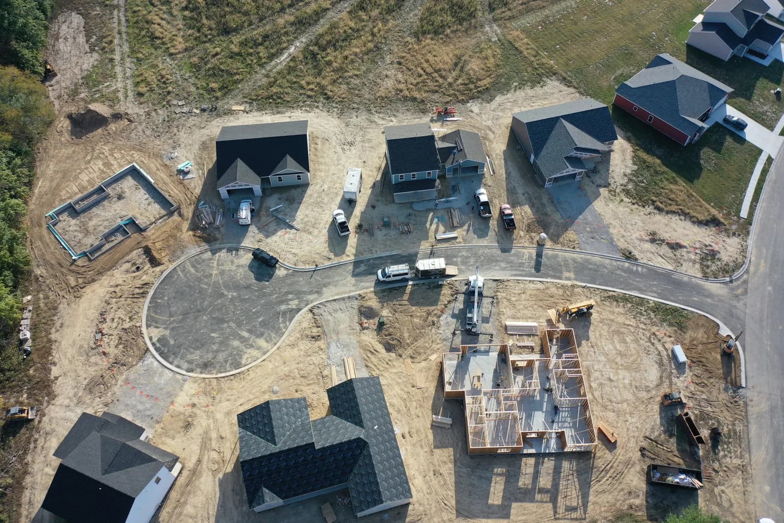 Top-down drone aerial of a Four Oaks cul-de-sac with several homes under construction and foundations being poured.