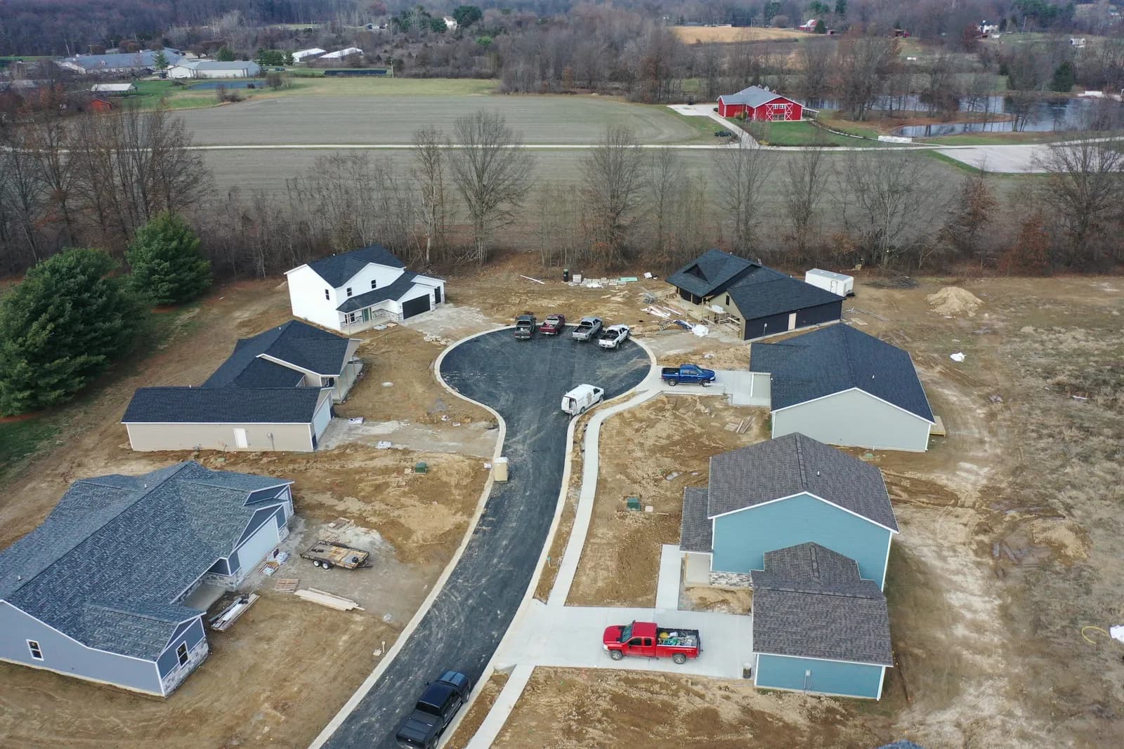 Drone aerial of a Four Oaks street with finished homes, fresh driveways, and cars parked out front.