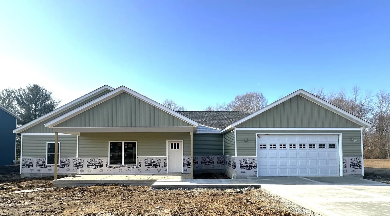 A newly built sage-green ranch home at Four Oaks with a covered front porch and attached two-car garage.