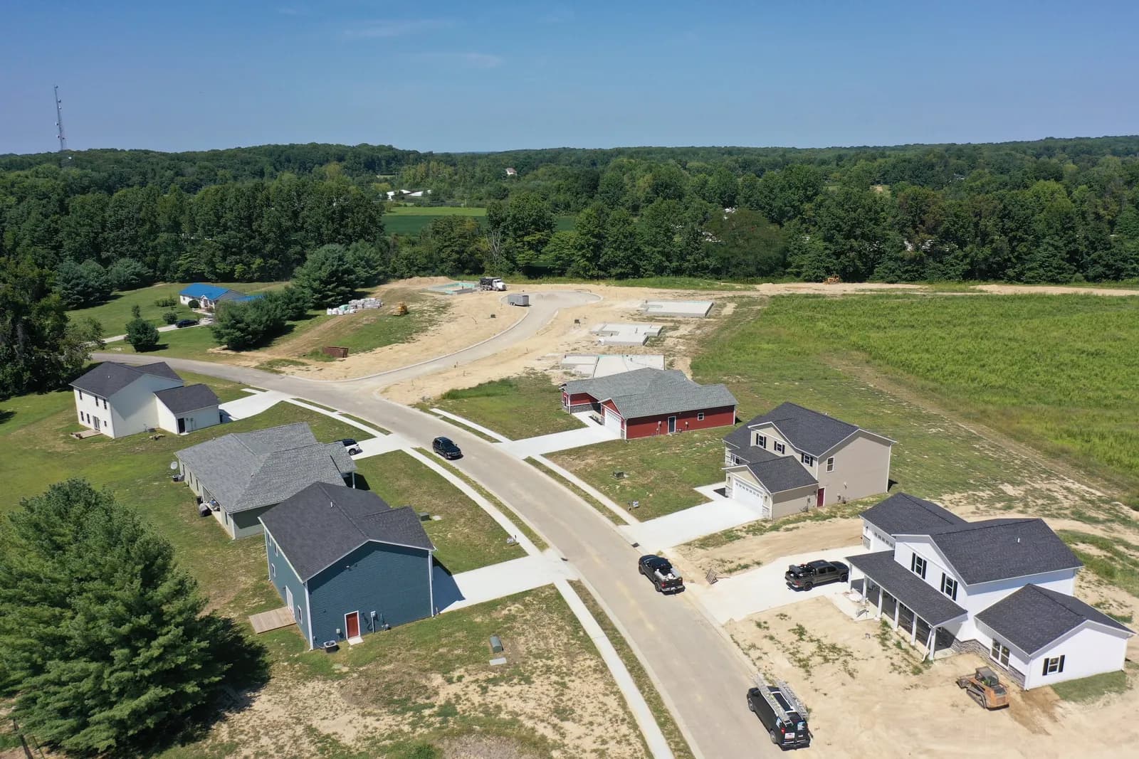 Drone aerial of a Four Oaks street with new homes and a red barn on the countryside beyond.