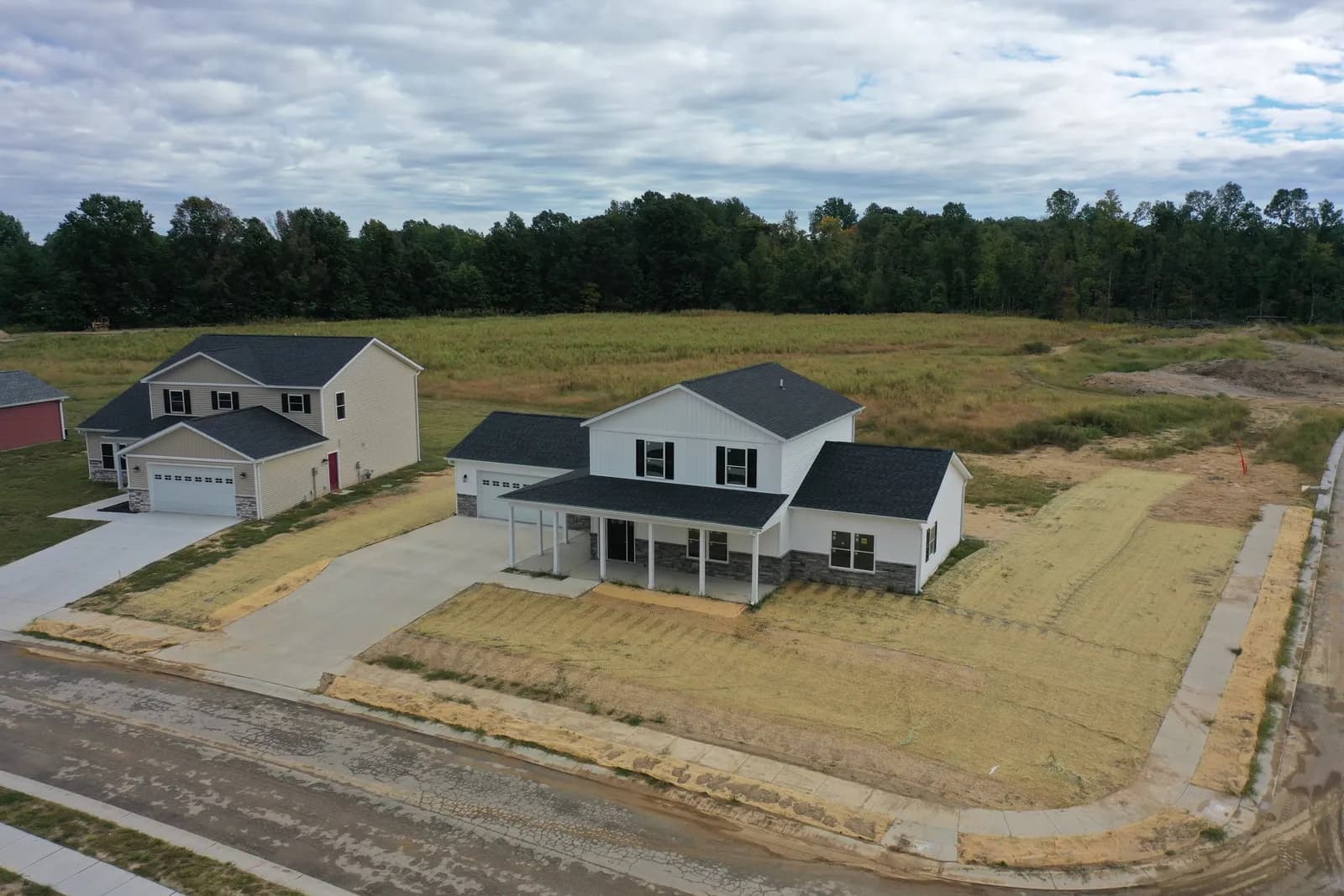 Drone aerial of a newly finished two-story home at Four Oaks with open fields behind it.