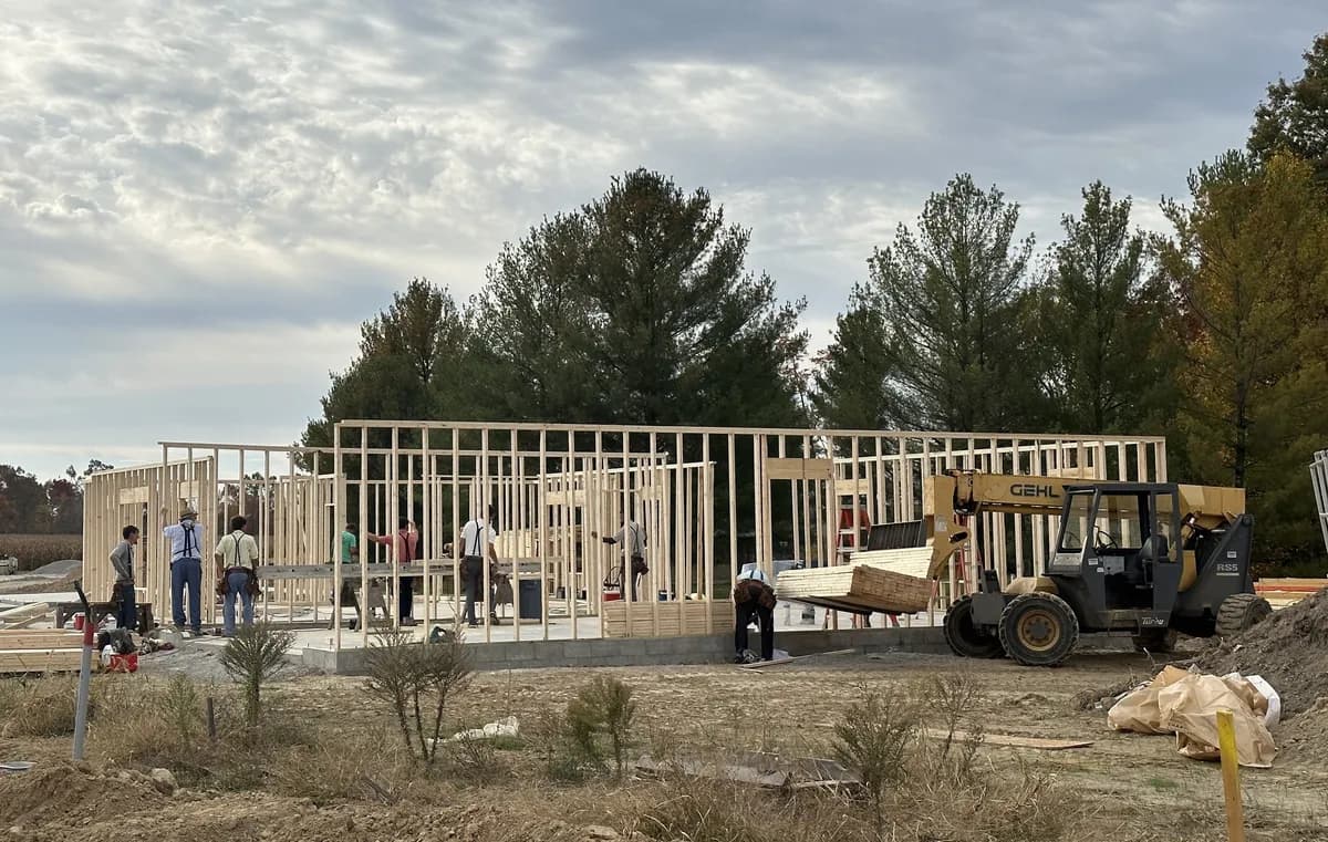 A framing crew raising the walls of a new home at Four Oaks on a sunny day.