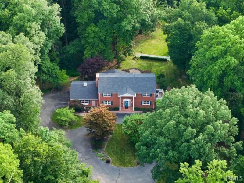 Aerial view of 1550 Park Hill Dr on its wooded 4.11 acre lot above downtown Spencer.