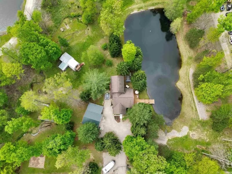 Aerial view of 681 Hancock School Rd showing the house, outbuildings, and the stocked pond on 4.56 wooded acres.