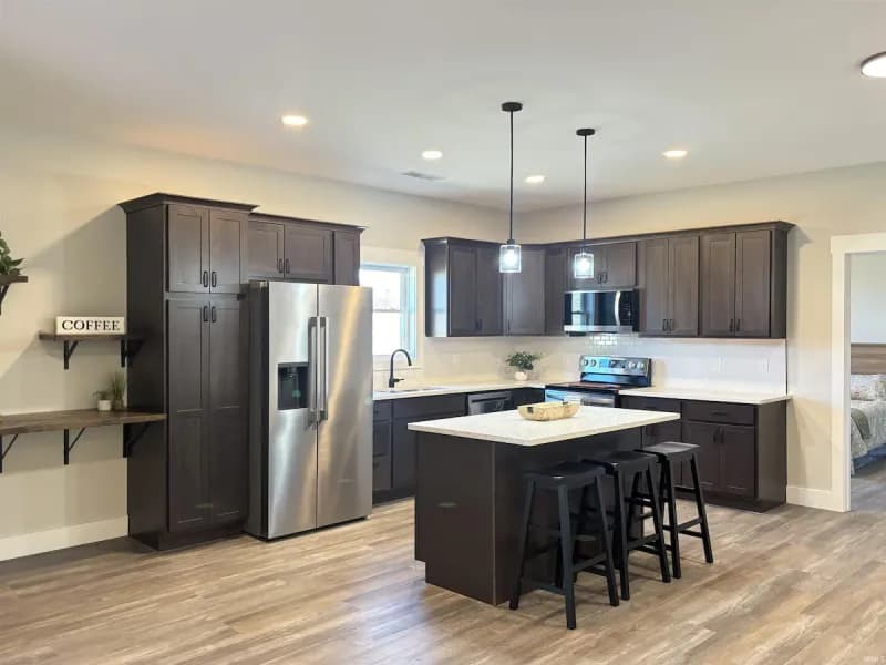 Kitchen with dark cabinetry, quartz countertops, a center island, and stainless steel appliances at 710 White Oak Rd.
