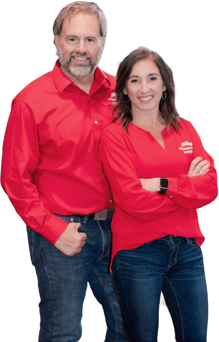 Rob Ranard and Samantha Carver of The HOME TEAM Properties, standing together with arms crossed in their red team shirts.
