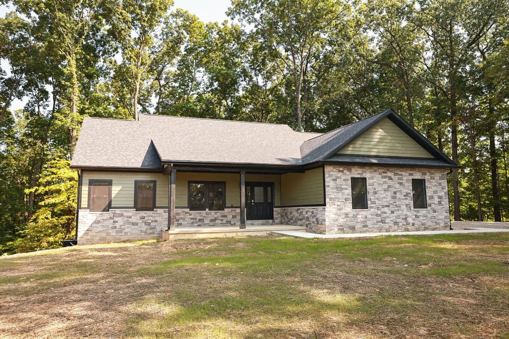 A stone-and-siding ranch home on a wooded lot.